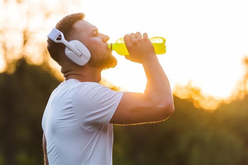 Person with headphones drinking from a plastic bottle